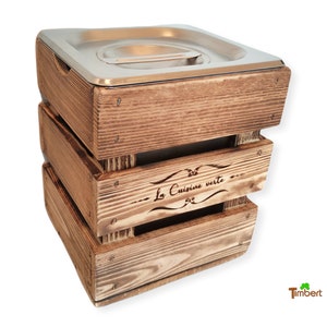 Op de afbeelding: Een drielaagse houten compostbak met een deksel van roestvrij staal. De bak is gemaakt van rustiek bruin hout en heeft de woorden "La Cuisine Verte" gegraveerd aan de zijkant.