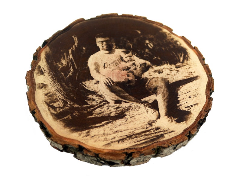 May include: A black and white photo of a man and a child is printed on a round wooden slice. The man is wearing a t-shirt with the word "Certain" printed on it.