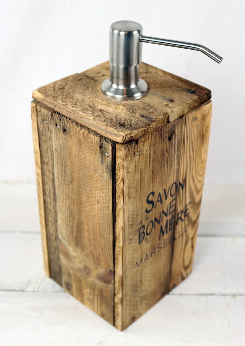 May include: A wooden soap dispenser with a stainless steel pump. The dispenser is made from reclaimed wood and has the text "SAVON BONNE MERE MARSEILLE" printed on the side.