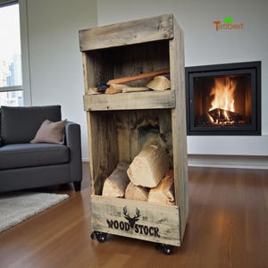 Op de afbeelding: Een rustieke houten houtopslag met twee compartimenten. De bovenste plank bevat een bijl en gespleten blokken, terwijl het onderste gedeelte gevuld is met brandhout. De unit staat op wielen en heeft de tekst "WOOD STOCK 69" op de voorkant.