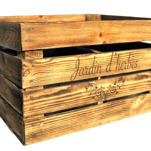 May include: A rustic wooden crate with a distressed brown finish. The crate has a label that reads "Jardin d'herbes" with a decorative floral design.
