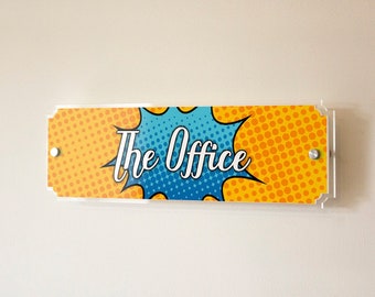 May include: A yellow and blue office sign with a comic book style speech bubble that says "The Office".