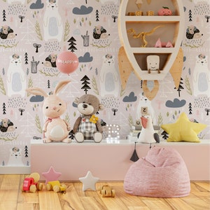 May include: A pink and white wallpaper with a woodland theme featuring bears, trees, and clouds. The wallpaper is displayed in a room with a pink beanbag chair, a wooden shelf with toys, and a stuffed rabbit and bear.
