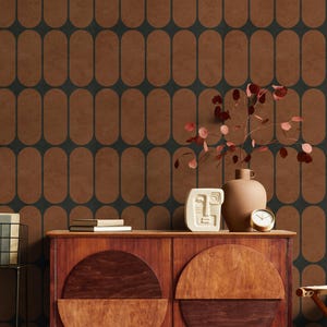May include: A mid-century modern style room with a brown and dark teal oval pattern wallpaper. A wooden cabinet holds a vase, a clock, and a white face sculpture. A plant with red leaves sits in a brown vase.