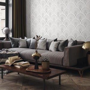 May include: A grey sofa with cushions sits in a living room with a grey and white patterned wallpaper. A wooden coffee table with a vase and a plant sits in front of the sofa.