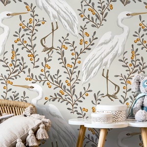 May include: A nursery wallpaper with a white background featuring a repeating pattern of white herons standing on branches with small orange berries. The branches are gray and the berries are orange.