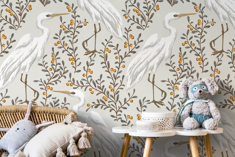 May include: A nursery wallpaper with a white background featuring a repeating pattern of white herons standing on branches with small orange berries. The branches are gray and the berries are orange.