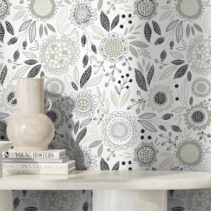 May include: A white background with a black and grey floral pattern. The pattern features stylised flowers, leaves, and berries. The background is a light grey colour.