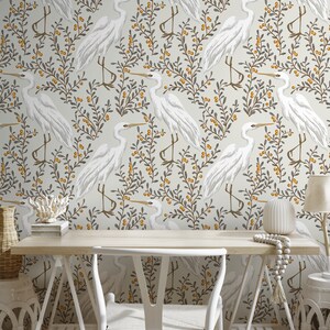 May include: White wallpaper with a repeating pattern of white birds, grey branches, and yellow berries. The wallpaper is in a room with a white desk, a white chair, and a white vase.