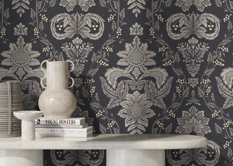 May include: A black and white damask wallpaper with gold accents. A white vase, a white pedestal, and three books are on a white table in front of the wallpaper. The books are titled "Young Hosters", "Walden", and "Golden Years of France".