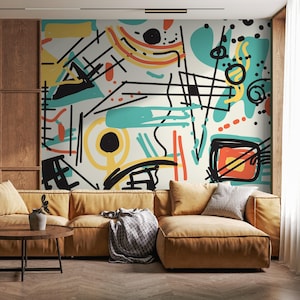 May include: A modern living room featuring a mustard-colored sectional sofa, a round wooden coffee table, and a wall mural with an abstract design. The mural showcases a mix of black, yellow, teal, and orange shapes and lines against a cream background.