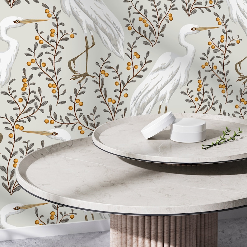 May include: White ceramic table with two round tiers. The table has a light wood base. The background is a white wallpaper with a repeating pattern of white birds and gray branches with orange berries.