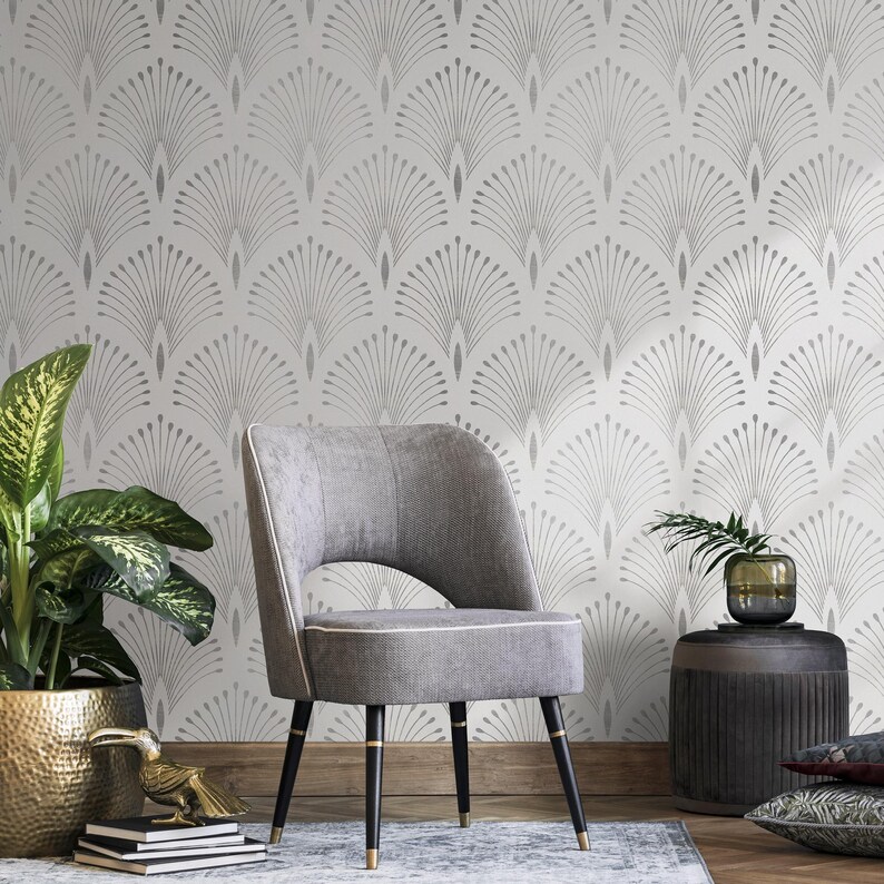 May include: A grey armchair with a white fabric seat and black legs sits in front of a white wall with a silver geometric pattern. A potted plant and a side table with a vase are also in the room.