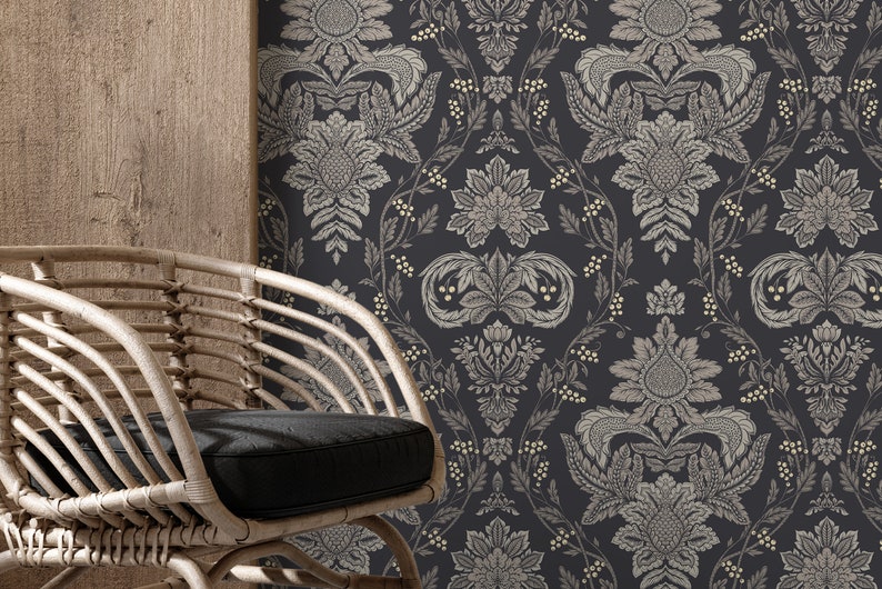 May include: A wicker chair with a black cushion sits in front of a wall with a dark blue and cream floral wallpaper pattern.