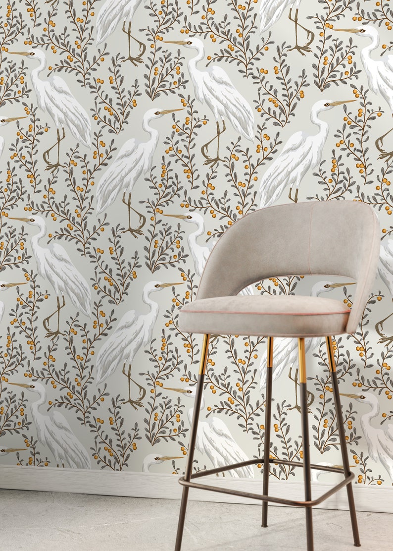 May include: White egret birds on a beige background with grey and yellow foliage. The birds are repeated in a pattern. A bar stool with a beige seat and black and gold metal legs is in the foreground.
