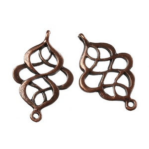 Peut inclure: Deux breloques en métal filigrané de couleur cuivre avec un design décoratif et complexe. Les breloques ont une boucle en haut pour être attachées à des bijoux ou d'autres objets artisanaux.