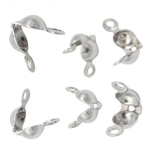 Könnte beinhalten: Sechs silberne Perlenkappen aus Metall mit einer Öse an einem Ende und einer kleinen Kugel am anderen Ende. Die Kappen sind so konzipiert, dass sie als Endkappen für Halsketten, Armbänder oder anderen Schmuck verwendet werden können.