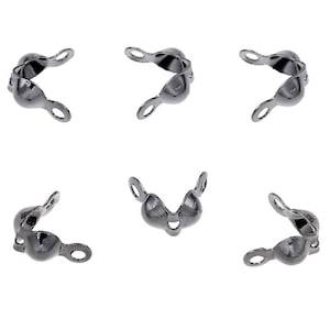 Könnte beinhalten: Sechs Schmuckstücke in Gunmetal-Farbe, jeweils mit einer gebogenen Form und einer kleinen Schlaufe an jedem Ende. Die Schmuckstücke sind vor einem weißen Hintergrund angeordnet, um ihren metallischen Glanz und ihr Design hervorzuheben.