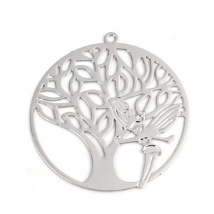 Peut inclure: Pendentif argenté représentant un arbre et une silhouette de fée. Le pendentif circulaire est doté d'une petite boucle en haut pour l'accrocher. Les branches et les feuilles de l'arbre sont finement découpées, et la fée est positionnée à droite.