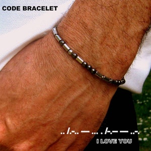 Peut inclure: Un bracelet en perles argentées et noires avec le message "I LOVE YOU" en code Morse.