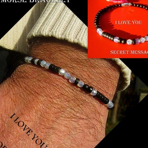 May include: A black and white beaded bracelet with a magnetic clasp. The bracelet has a secret message in Morse code that reads "I love you".