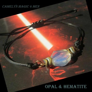 Peut inclure: Bracelet en cordon noir orné d'une pierre d'opale et d'hématite irisée. Le bracelet comporte des accents métalliques dorés et des nœuds réglables. Les textes "CAMELYS MAGIC 4 MEN" et "OPAL & HEMATITE" sont visibles.