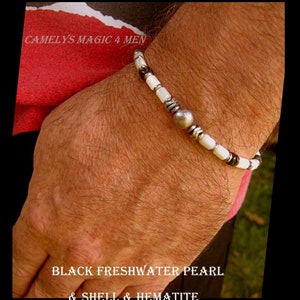 May include: A bracelet featuring black freshwater pearls, white shell beads, and hematite beads. The bracelet has a silver bead in the centre.