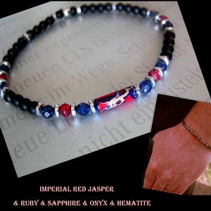 May include: A black onyx beaded bracelet with a red jasper, ruby, and sapphire accent. The bracelet also features a silver spacer bead and a silver clasp.