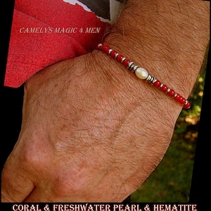 Peut inclure: Un bracelet composé de perles de corail rouge, d'une perle d'eau douce blanche et de perles argentées. Le bracelet est porté au poignet.