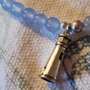 May include: A light blue beaded bracelet with a silver lighthouse charm.