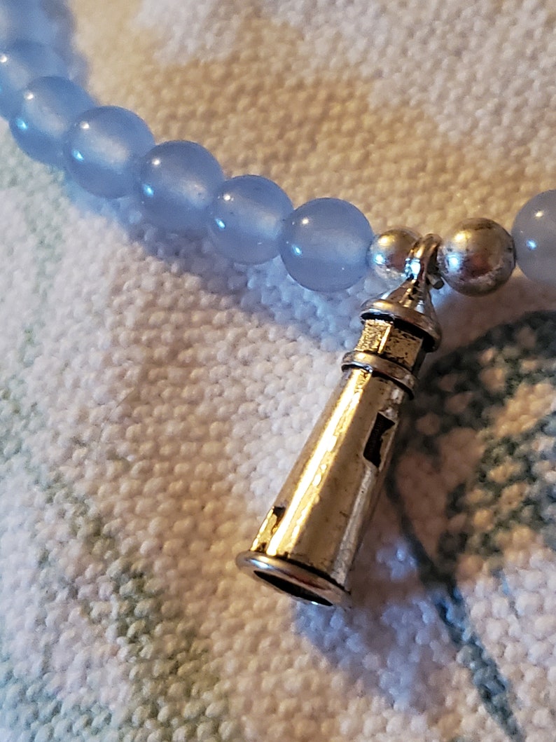 May include: A light blue beaded bracelet with a silver lighthouse charm.
