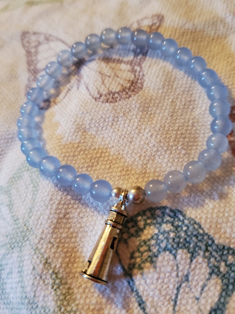 May include: A light blue beaded bracelet with a silver lighthouse charm.