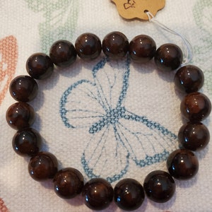 May include: A brown gemstone bracelet with a tag that reads "Brown  Jacinth".