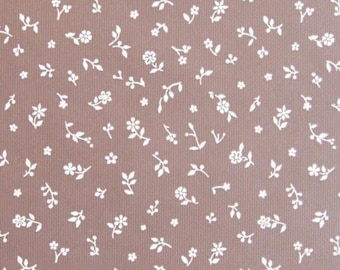 May include: A brown fabric with a white floral pattern. The pattern features small flowers and leaves scattered across the fabric.