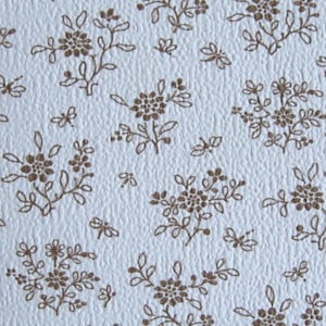 May include: A close-up of a textured, off-white surface with a repeating pattern of brown floral and leaf designs. The floral elements are clustered and scattered across the surface, creating a vintage aesthetic.