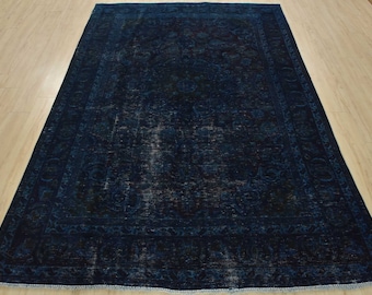 May include: A dark blue vintage rug with a faded floral pattern. The rug has a distressed look and a fringed edge.