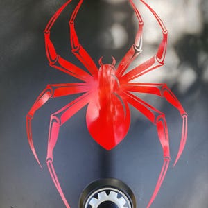 a close-up view of a black surface with a red spider design prominently displayed.