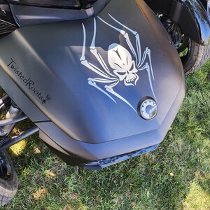 A close-up view of a motorcycle with a skull and spider design on the front.