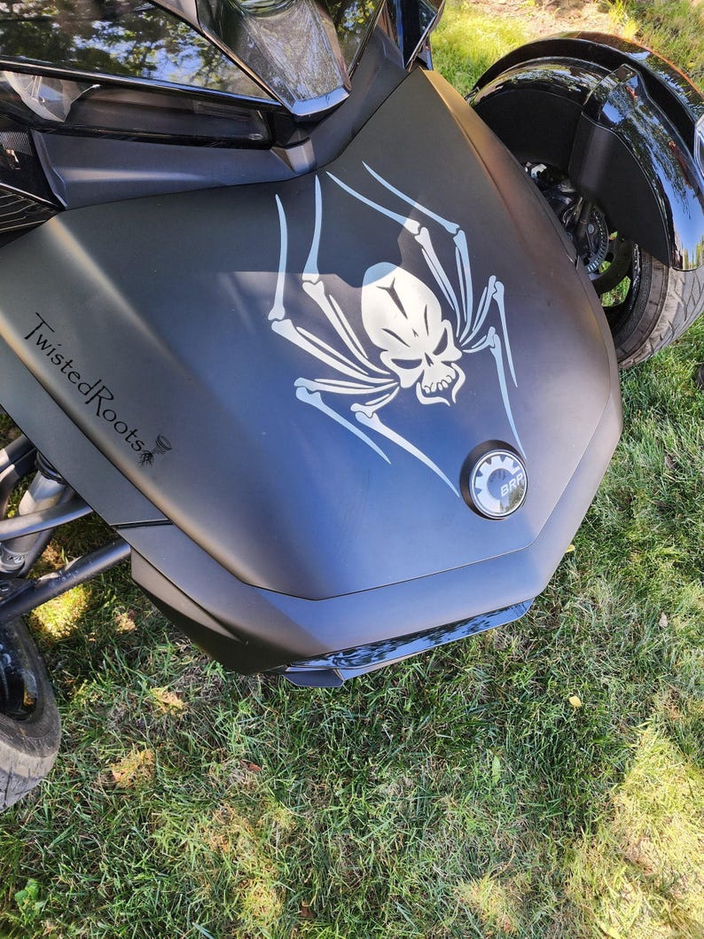 A close-up view of a motorcycle with a skull and spider design on the front.