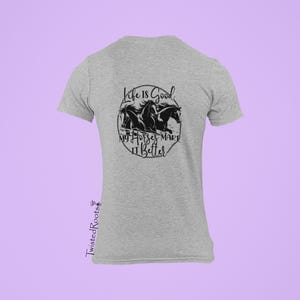 May include: A heather gray short-sleeve t-shirt featuring a black graphic of three horses in a circular frame. The text reads Life Is Good My Horses Make It Better. The brand name TwistedRoots is printed vertically in black on the lower left side.