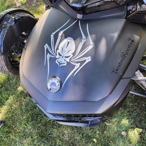 A close-up view of a motorcycle with a skull and spider design on the front.