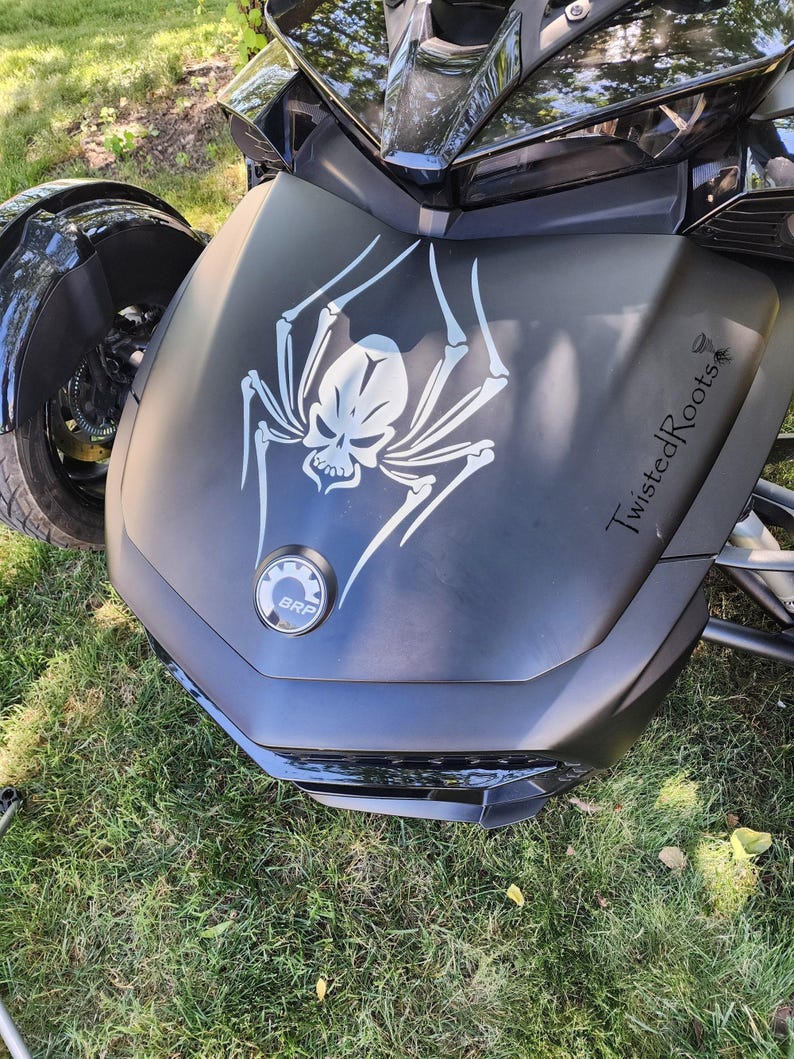 A close-up view of a motorcycle with a skull and spider design on the front.