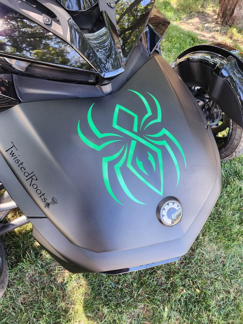 A close-up view of a motorcycle with a distinctive green and black design on the front, including a spider-like symbol.