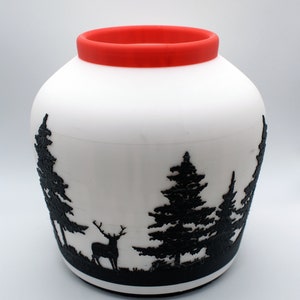 May include: White ceramic vase with a red rim and a black silhouette of a deer and trees.