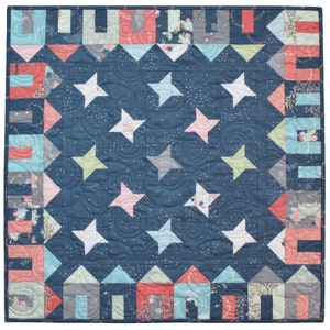 May include: A blue quilt with a star pattern. The quilt has a border of colorful squares and a white background with small white dots.