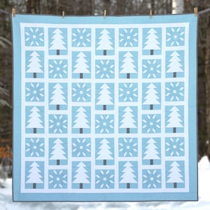 May include: A light blue and white quilt featuring a repeating pattern of white Christmas trees and snowflake motifs. The quilt has a light blue border and is suspended on a clothesline. This winter-themed quilt is a home decor item.