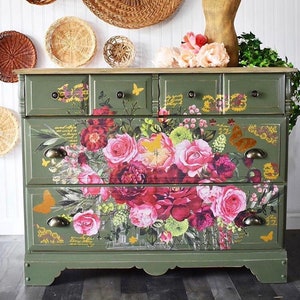 A green dresser with the royal burgundy transfer across the front of the drawers. Displayed on the wall are various weaved baskets. In the top right corner in white lettering, it reads New old finds by Roz Robertson.