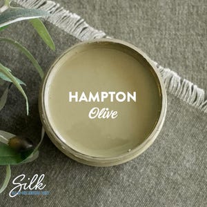 May include: A close-up of a jar of green paint labeled "Hampton Olive" by Silk All-in-One Mineral Paint.