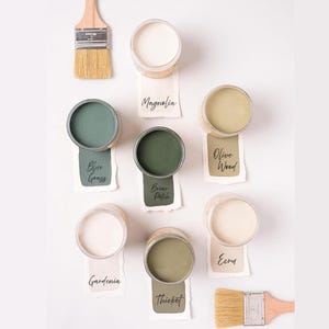 May include: Ten small jars of paint in various shades of green and white. The paint colors are labeled with names like "Blue Grass", "Briar Patch", "Olive Wood", "Magnolia", "Gardenia", "Thicket", and "Ecru".