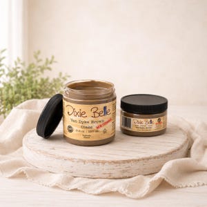 May include: Two jars of Dixie Belle Van Dyke Brown Glaze. One jar is open with a black lid next to it. The larger jar contains 8 fl oz (237 ml) of glaze. The smaller jar has a black lid and contains glaze.